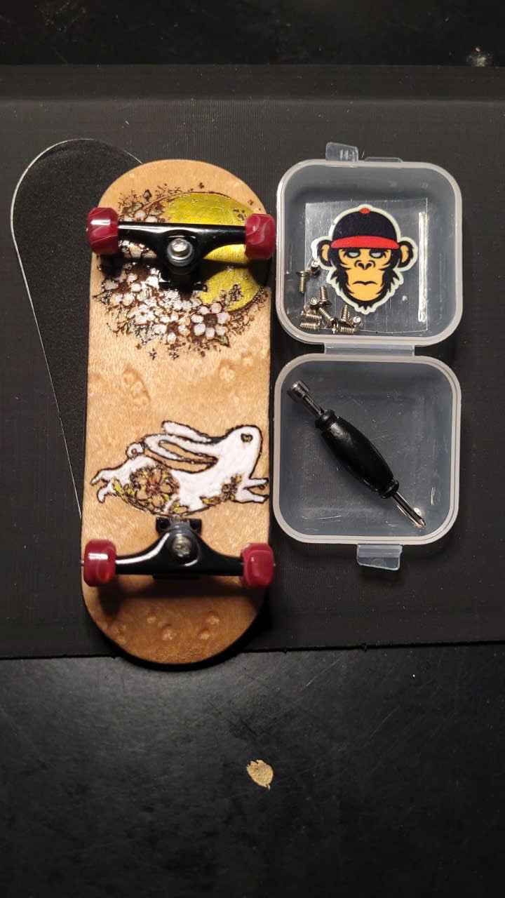 Custom handmade fingerboard deck with graphic art and miniature skate tool accessories.