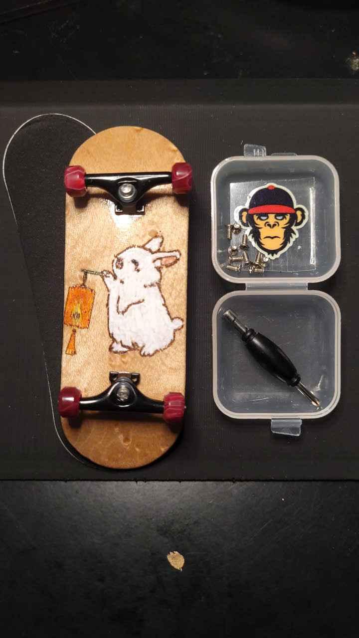 Custom handmade fingerboard deck with white rabbit graphic and mini screwdriver tool set.