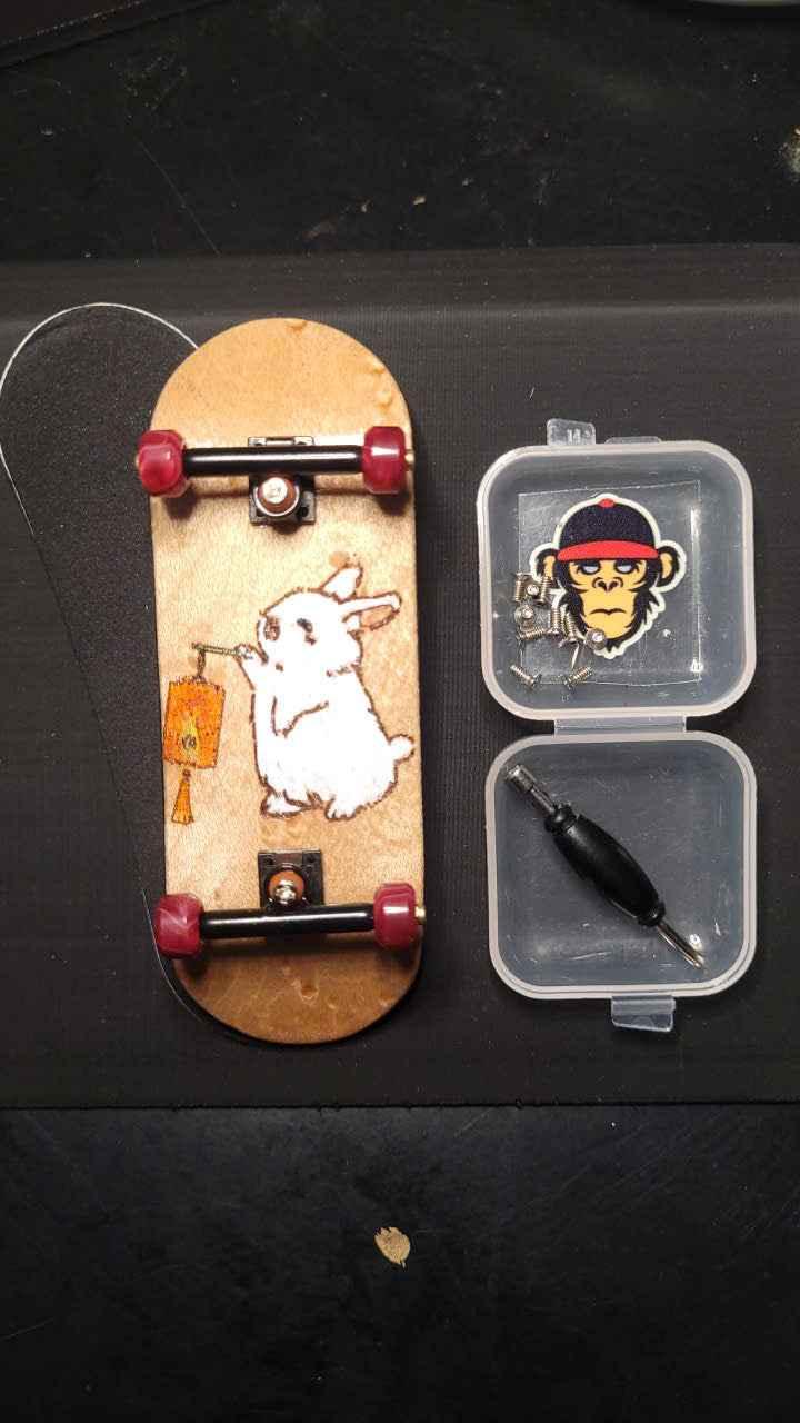 Custom handmade fingerboard deck with white rabbit graphic and red wheels with accessories.