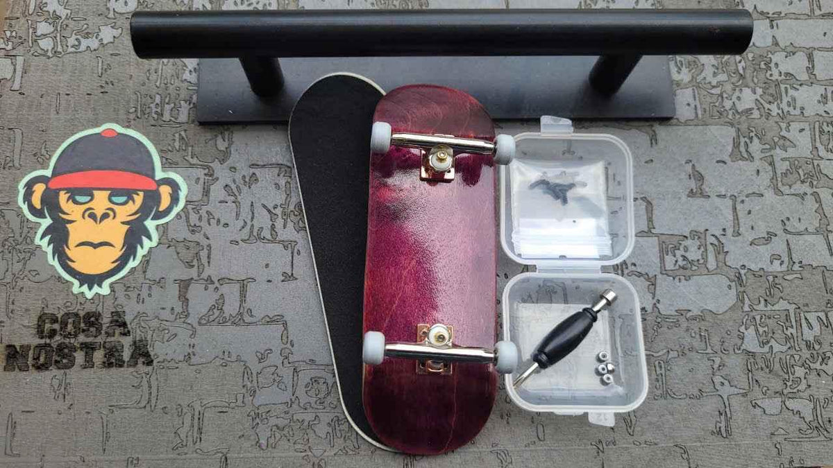 Custom handmade burgundy fingerboard deck with trucks, wheels, and assembly tools.