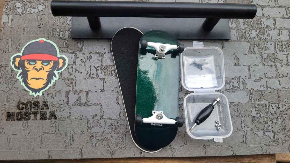 Green custom fingerboard deck with trucks, wheels, and assembly tools on a skate mat.