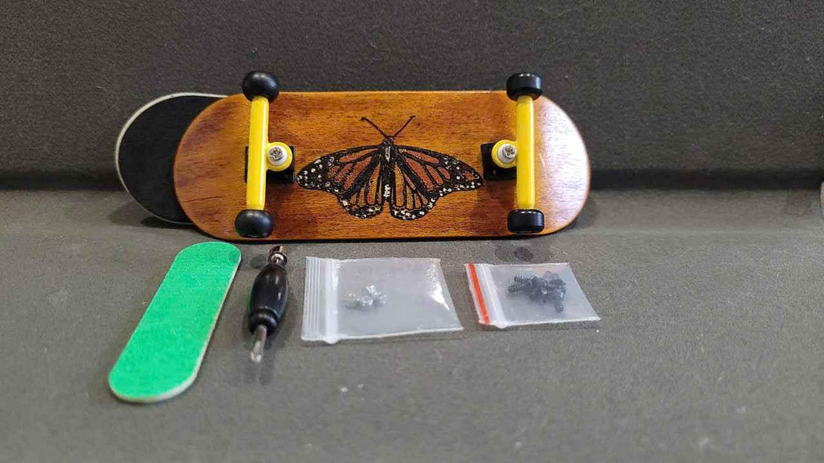Custom handmade fingerboard kit with butterfly deck, yellow trucks, and assembly tools.