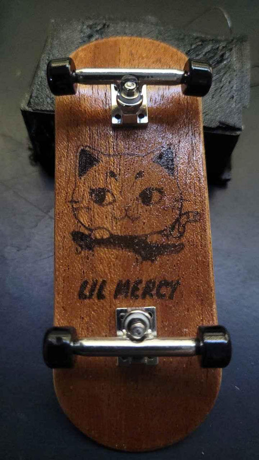 Custom handmade wooden fingerboard deck featuring a black cat graphic and Lil Mercy text.