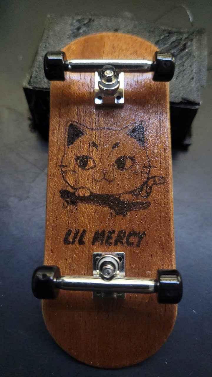 Custom handmade fingerboard deck with a black cat graphic and Lil Mercy text.