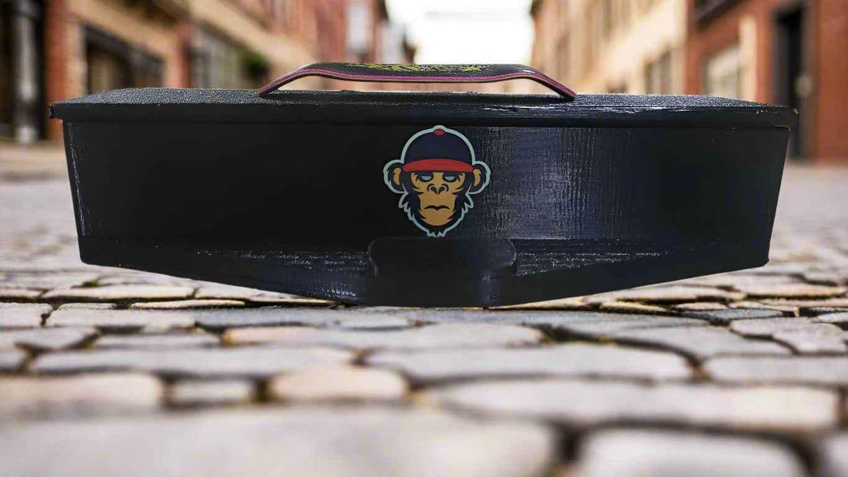 Black fingerboard training ramp with monkey graphic on a cobblestone street.