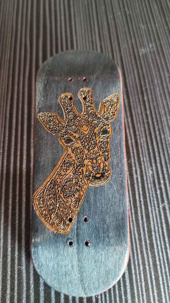 Custom handmade fingerboard deck with an intricate laser-engraved giraffe design.