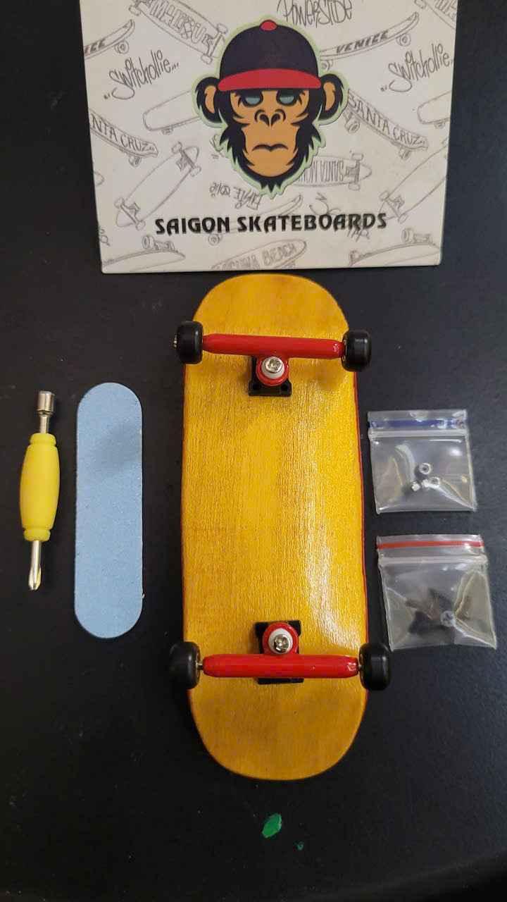Saigon Skateboards fingerboard kit with yellow deck, red trucks, griptape, and tools.