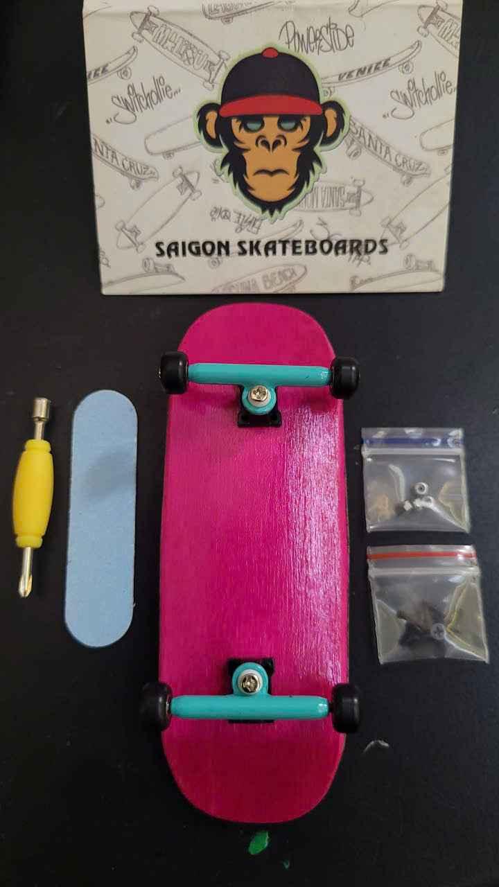 Custom pink fingerboard with blue wheels, tools, and accessories on a black surface.