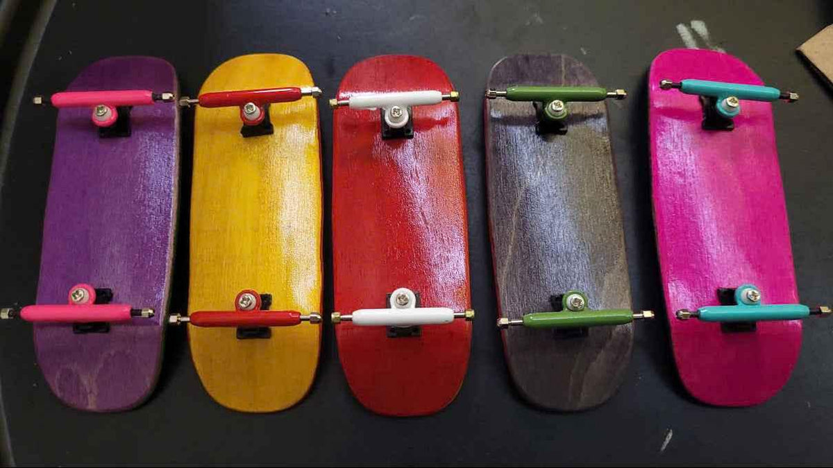 Five colorful custom handmade fingerboard decks with various colored trucks
