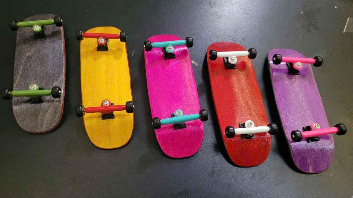 Five colorful handmade fingerboard decks with custom trucks and wheels.
