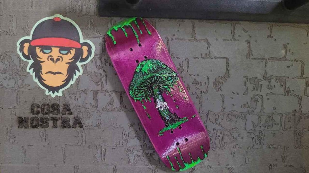 Custom purple fingerboard deck with a green dripping mushroom graphic