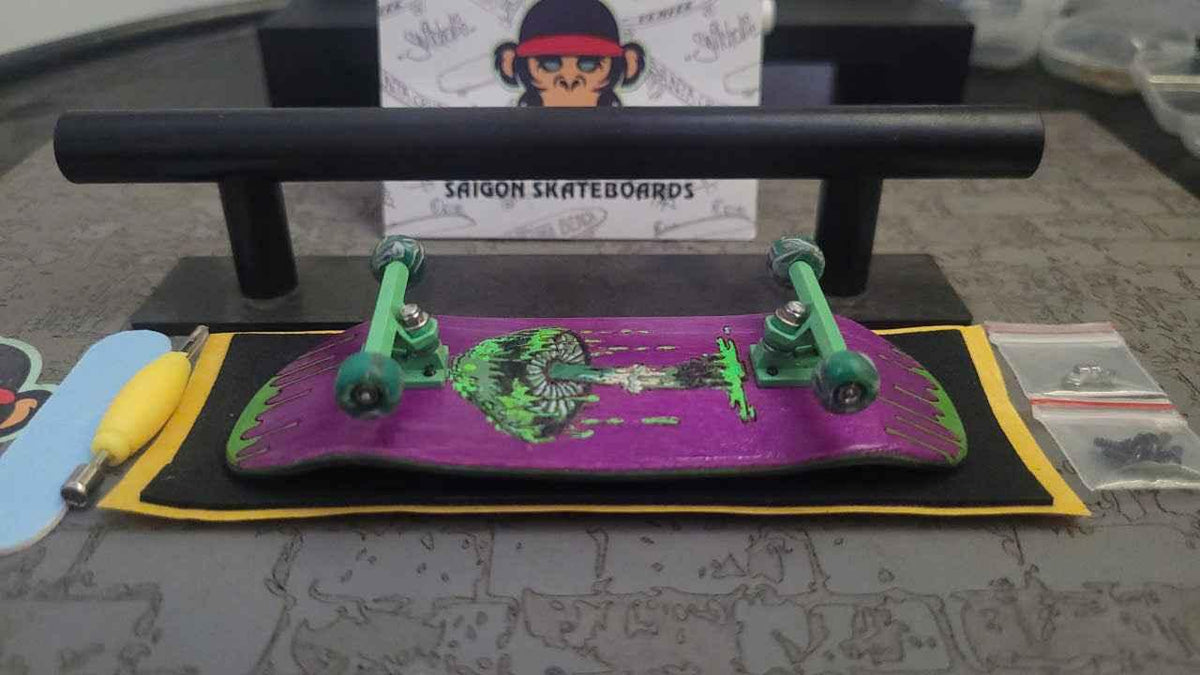 Custom purple fingerboard with green trucks on a black and yellow surface.