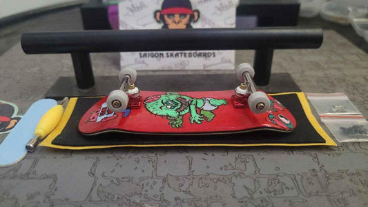 Custom red fingerboard deck with monster graphic and miniature skate accessories.