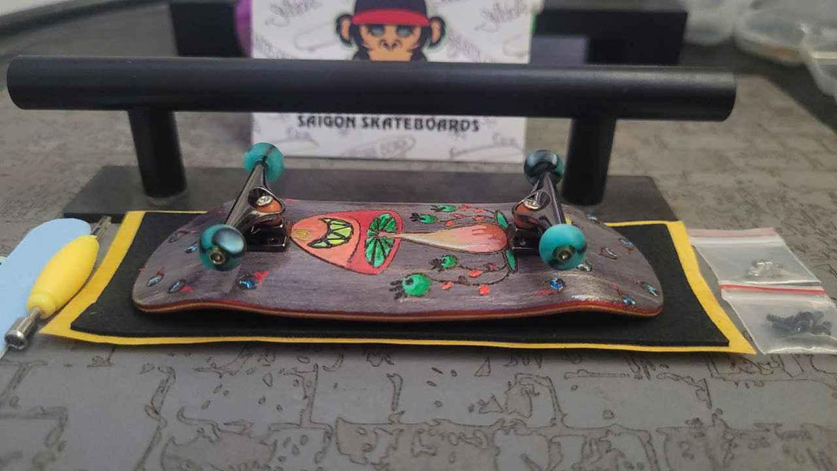 Handmade custom fingerboard deck with colorful graphics on a black surface.