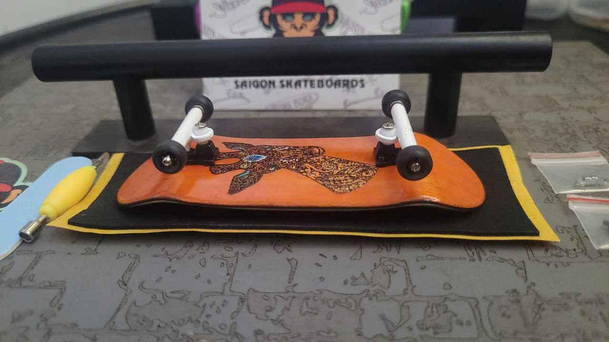 Handmade custom fingerboard deck with graphic design and white trucks on a yellow mat.