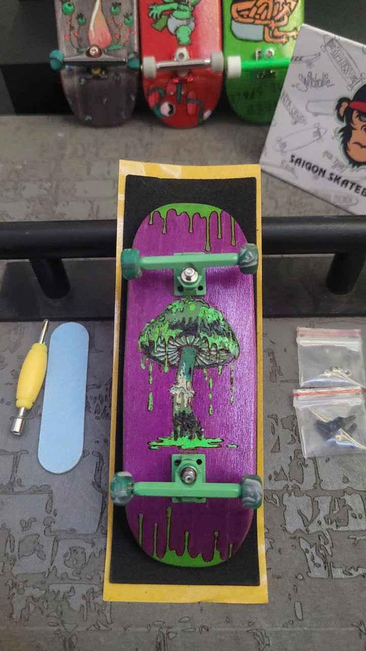 Custom handmade purple fingerboard deck with green mushroom graphic and matching trucks.
