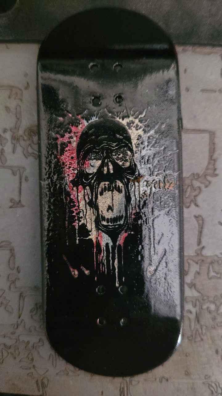 Custom fingerboard deck with a black skull and goggles graphic.
