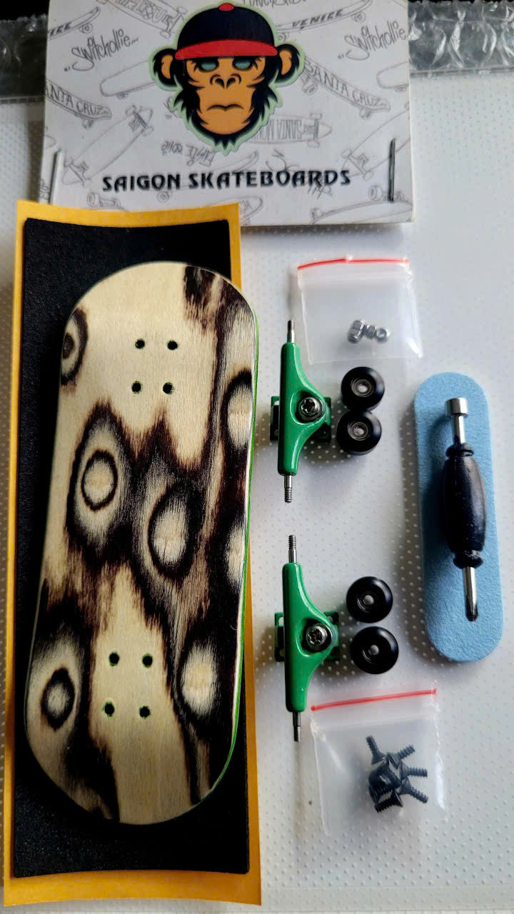 Fingerboard set with streak-pattern wooden deck, green trucks, wheels, grip tape, and tool