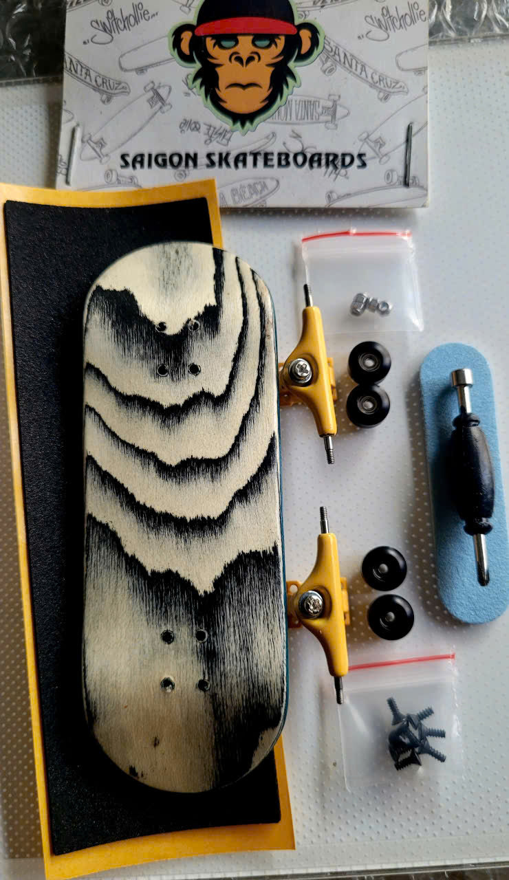 Fingerboard set with wavy black-and-cream deck, yellow trucks, wheels, tool, and hardware