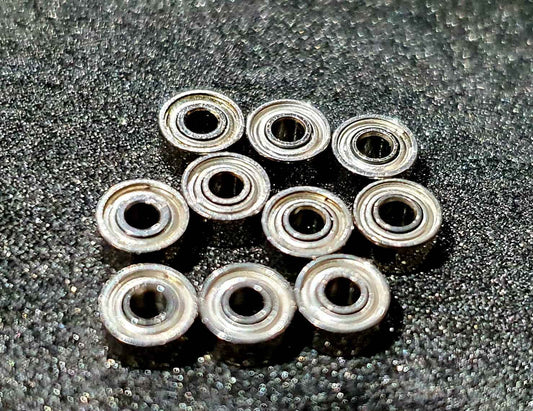 Ten small metal ball bearings arranged on a dark textured surface.