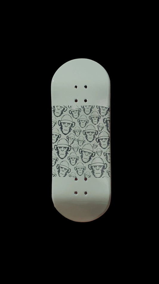 Fingerboard deck, off-white underside with cartoon face pattern and four mounting holes.