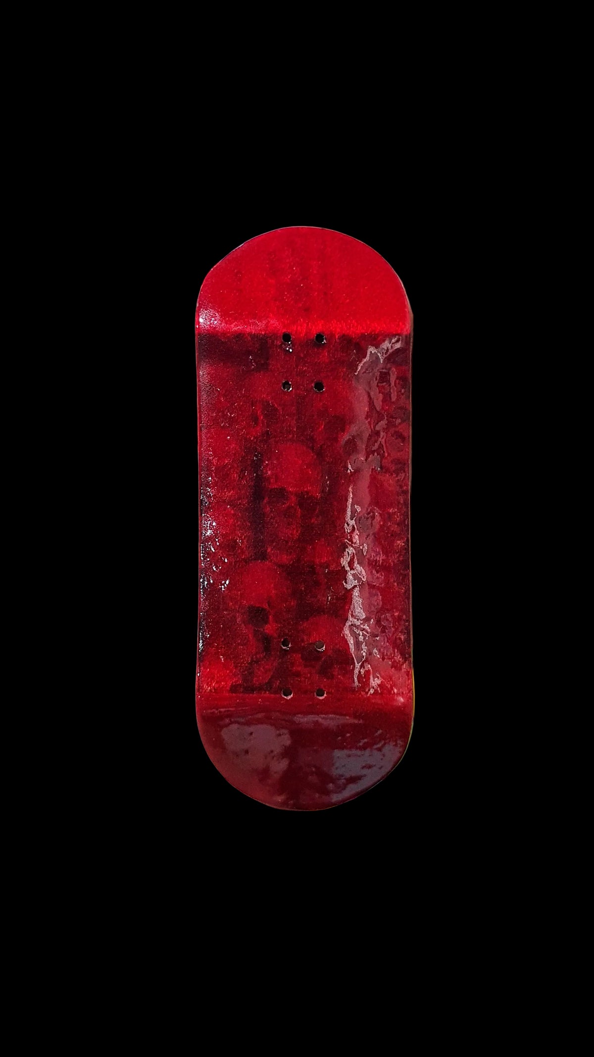Red fingerboard deck top view with weathered graphic and four mounting holes.