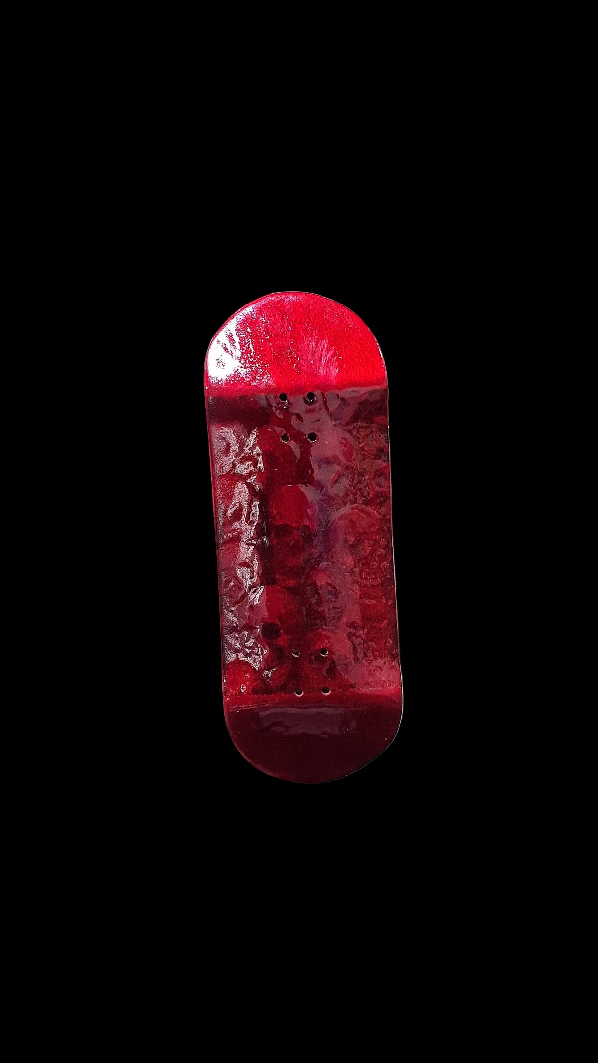Red fingerboard deck close front view with weathered finish and mounting holes.