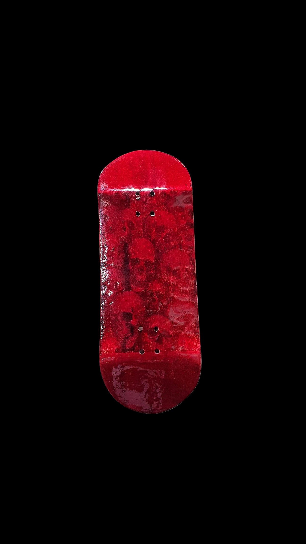 Red fingerboard deck front view with four metal mounting holes on top.
