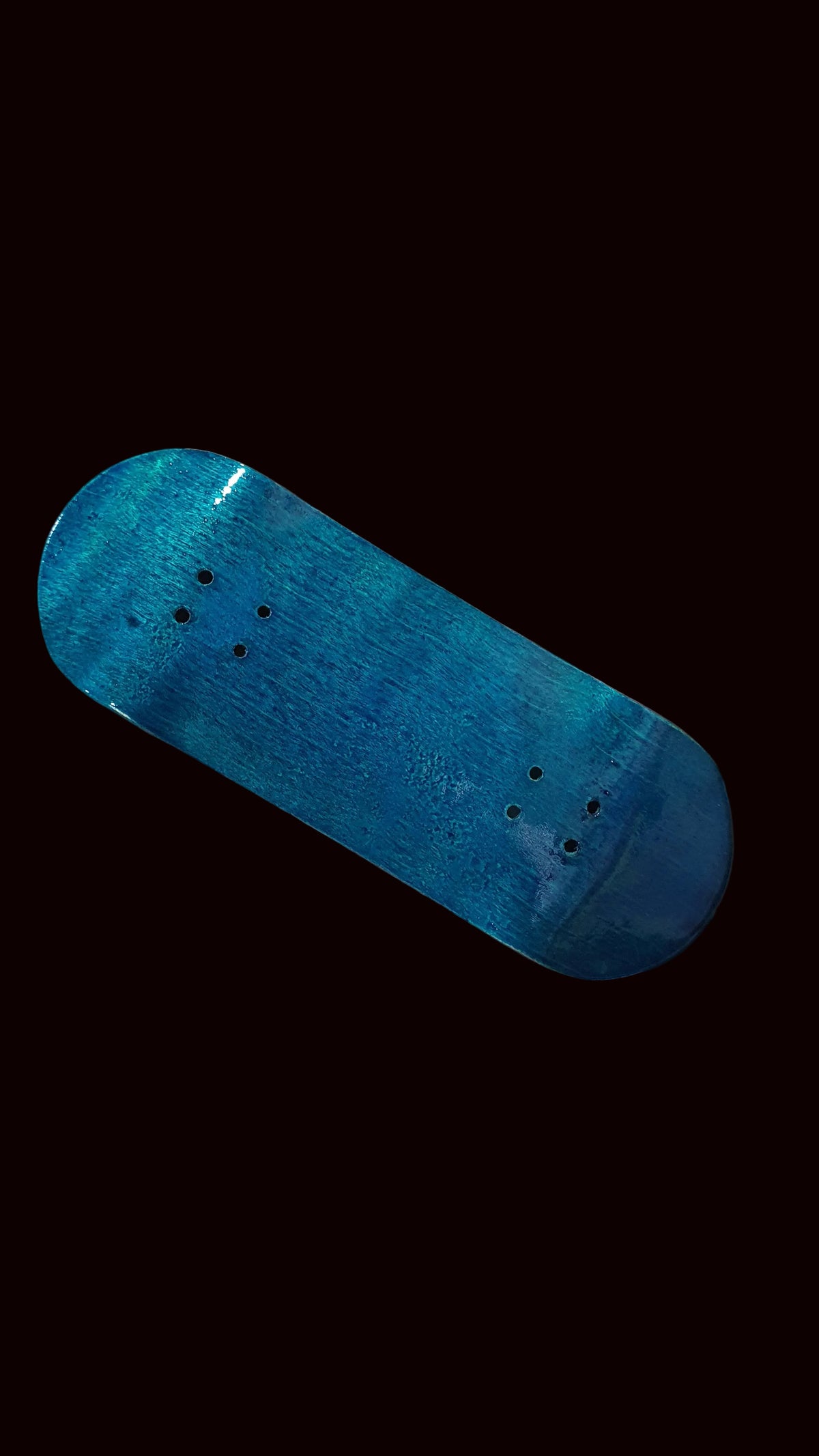 Blue teal fingerboard deck, angled view showing rounded edges and mounting holes.