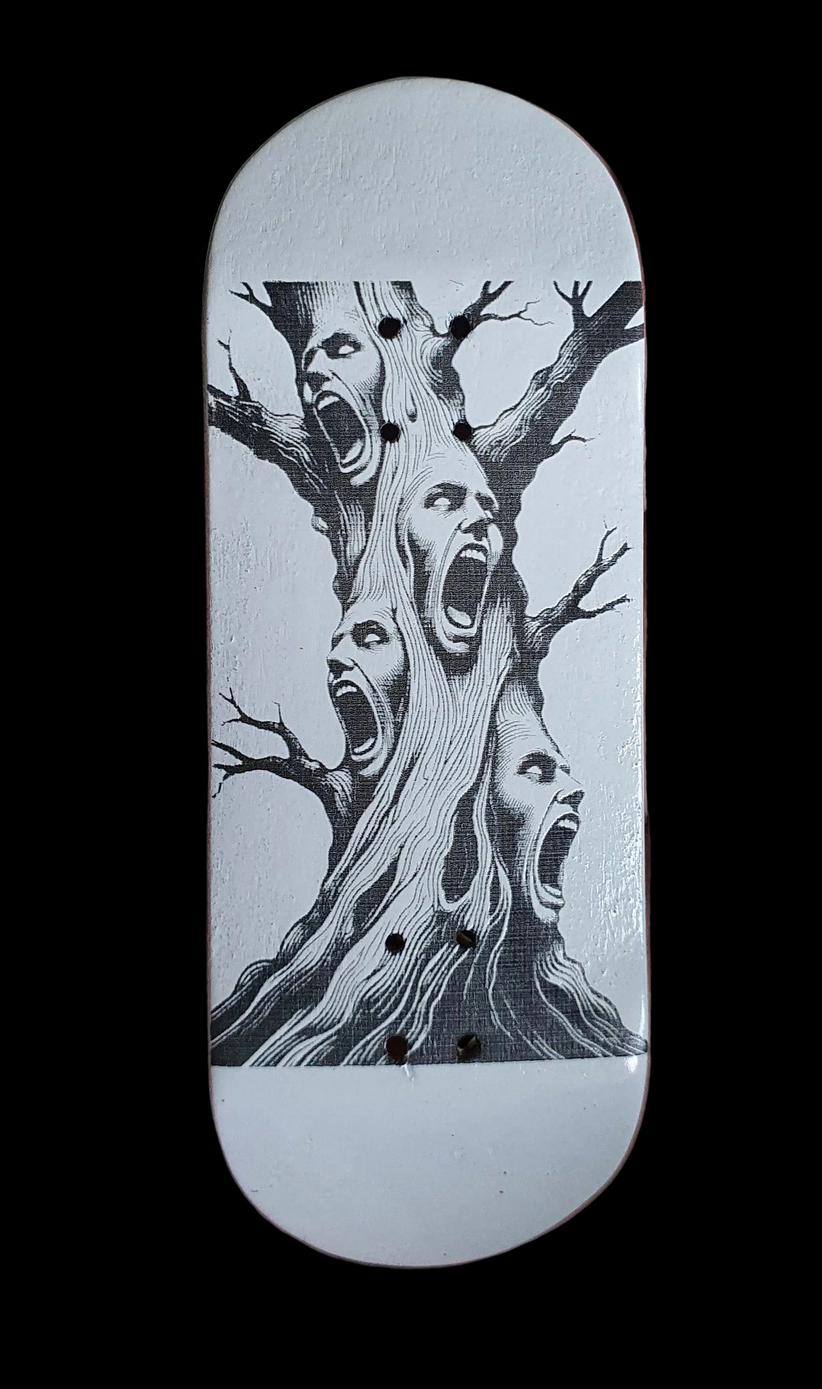 Skateboard deck with white base and black tree-screaming face graphic