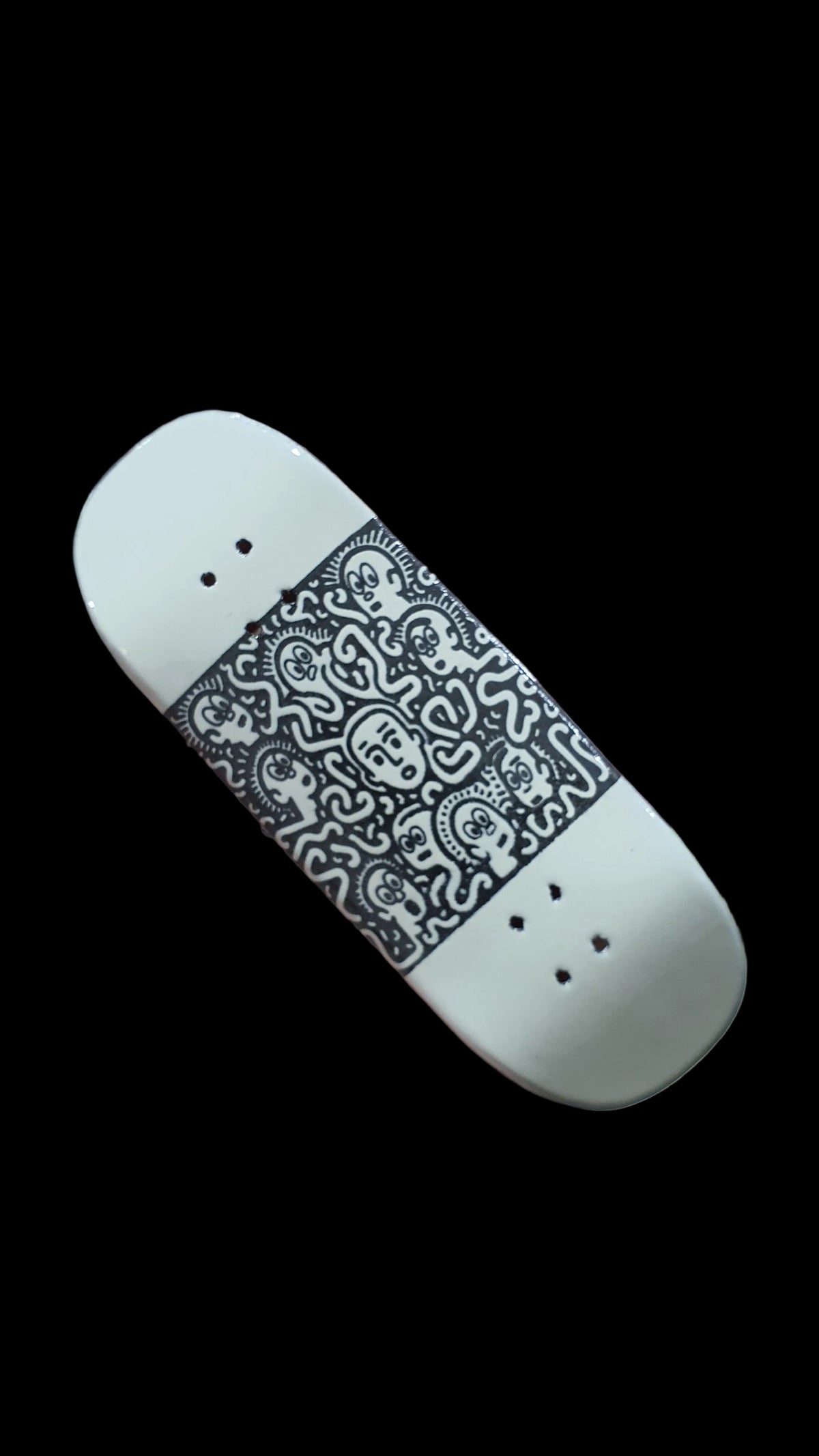 White Confusion fingerboard deck with black illustrated graphics and visible mounting holes
