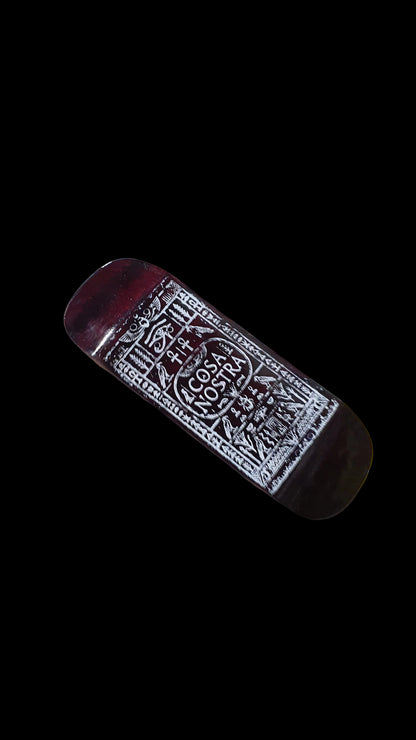 Angled fingerboard deck with ornate white Cosa Nostra graphic on a dark red-brown surface