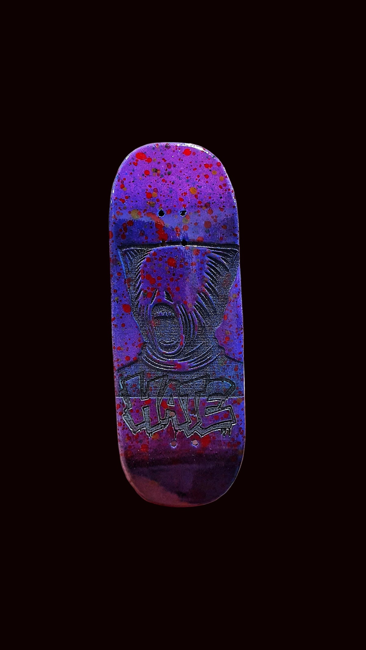 Purple fingerboard deck with red-blue speckle splatter and animal face graphic.