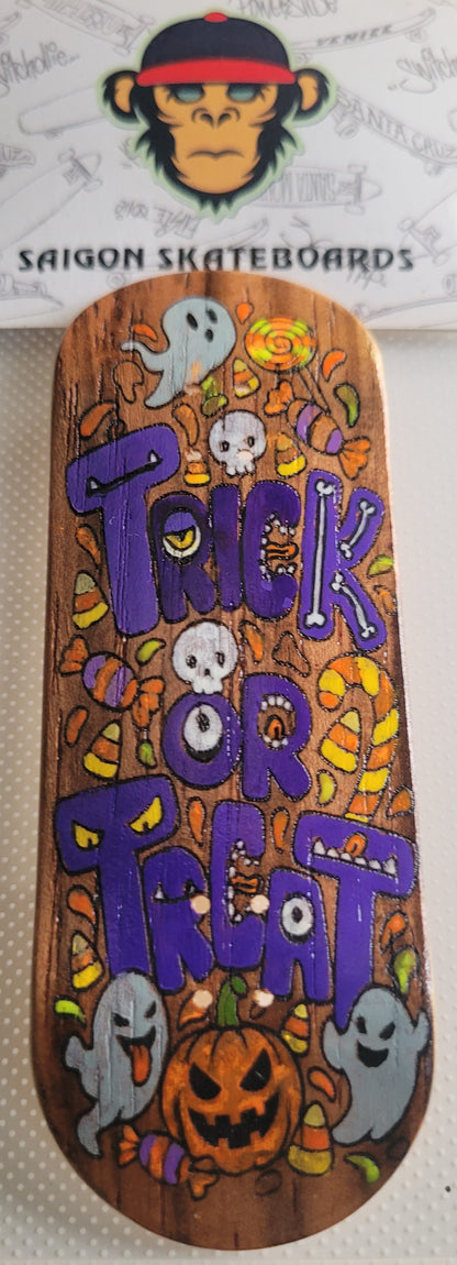 Skateboard deck with purple “TRICK OR TREAT” Halloween artwork, ghost and jack-o’-lantern