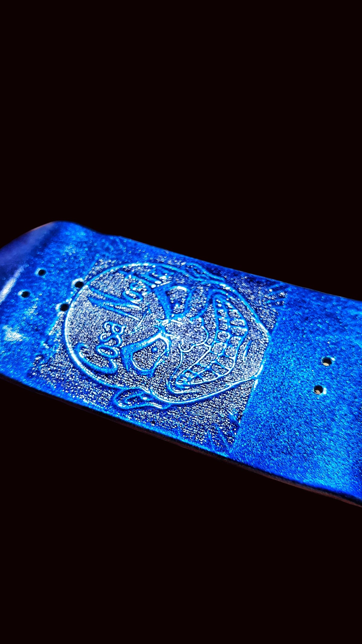 Blue fingerboard deck with embossed Cosa Nostra emblem and mounting holes, angled view