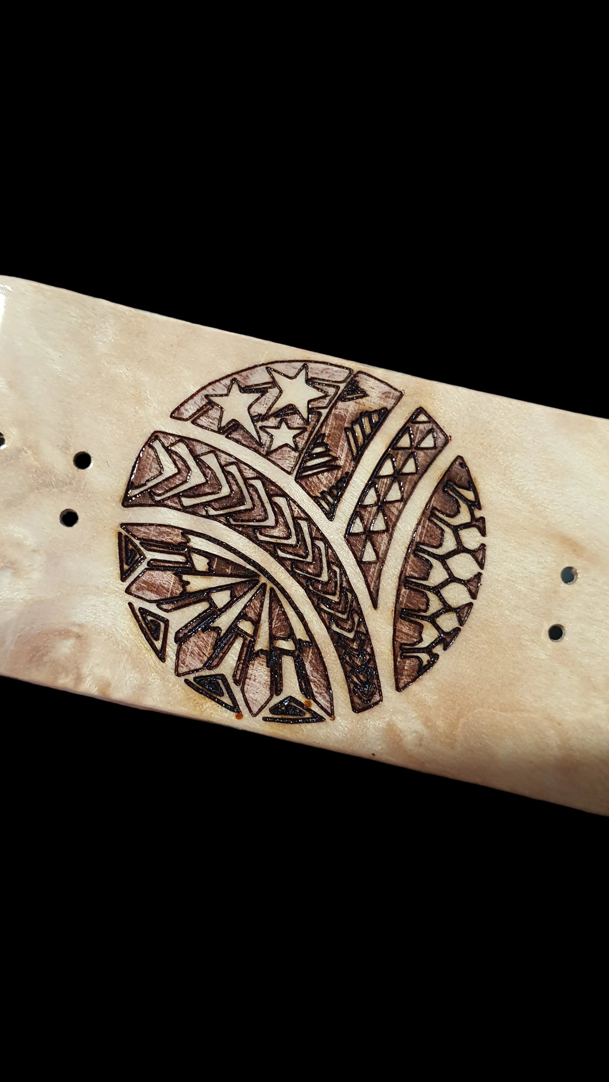 Fingerboard deck close-up of large tribal-style graphic on light wood