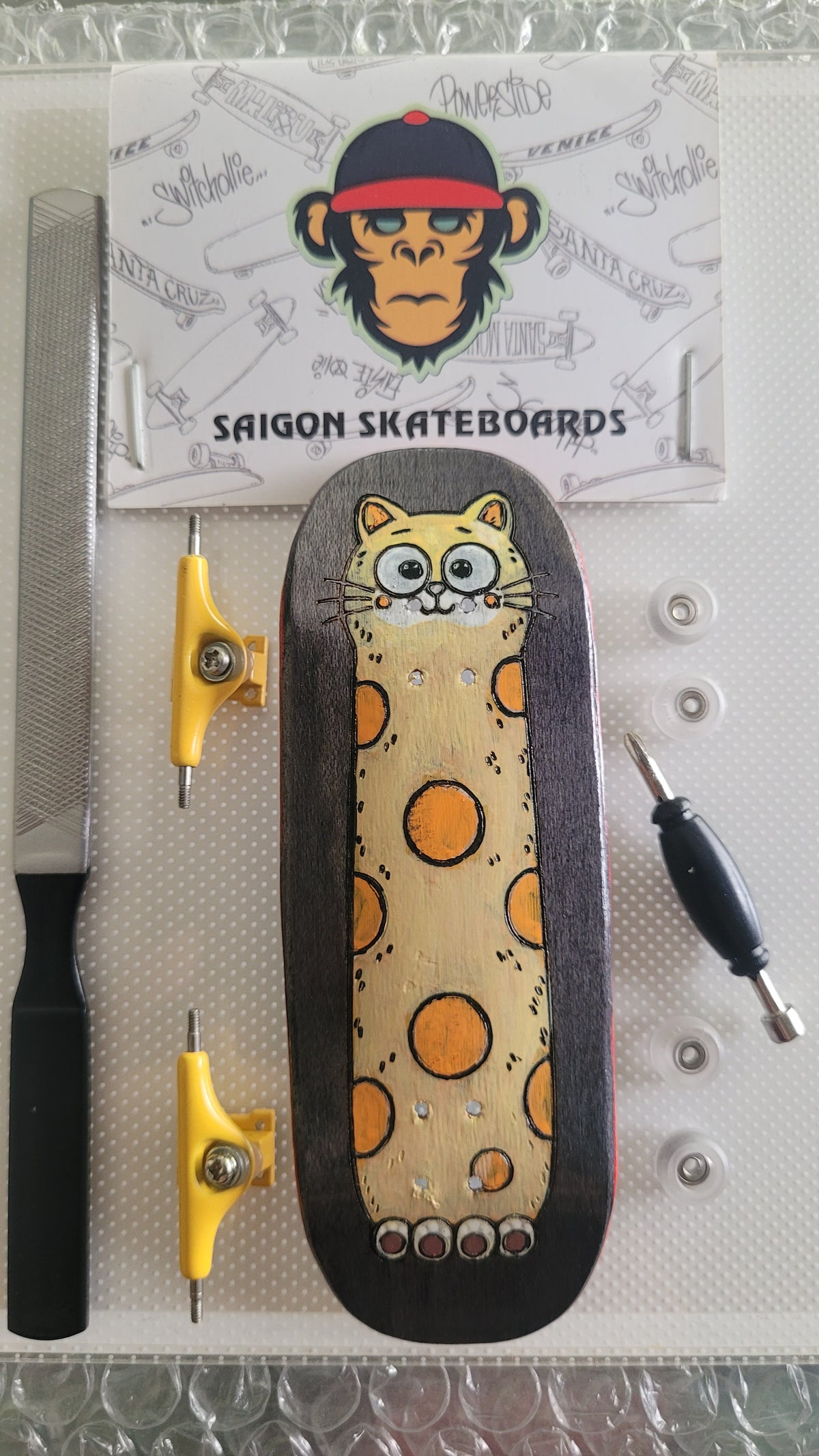 Complete fingerboard deck with cat graphic, yellow trucks and clear wheels