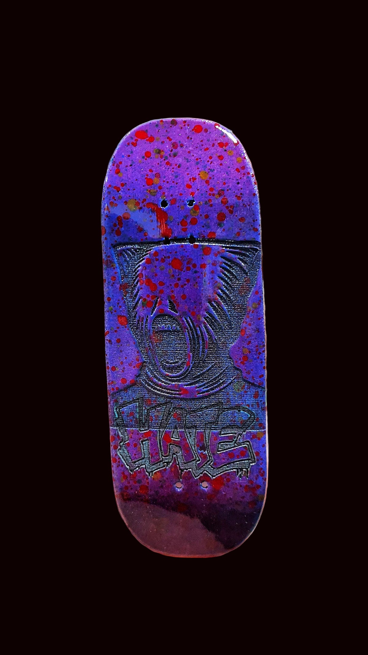 Purple fingerboard deck front view with animal face graphic and red-blue speckle background.