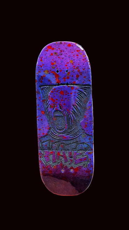 Purple fingerboard deck front view with animal face graphic and red-blue speckle background.