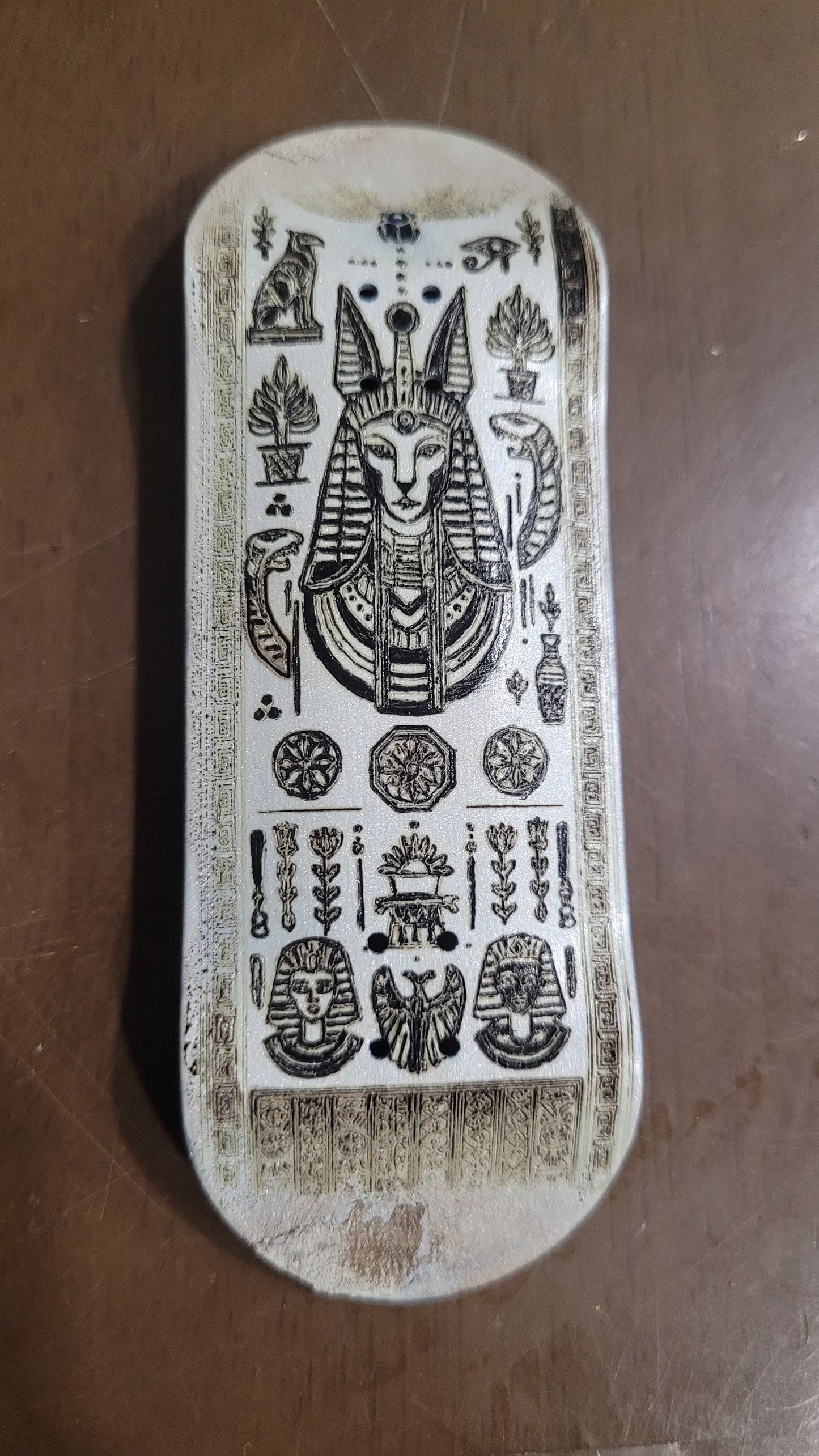 Decorative fingerboard with intricate carvings on a brown surface