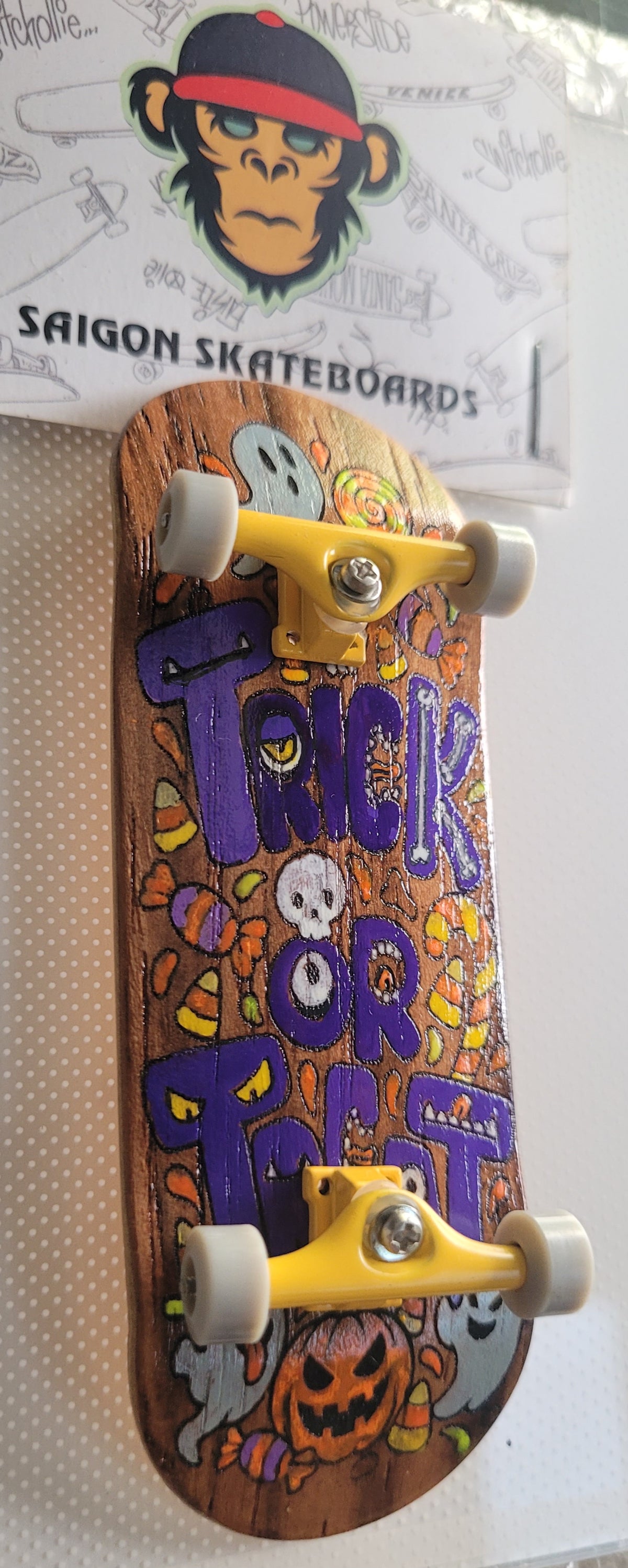 Complete skateboard with orange Halloween deck, purple lettering, silver trucks, and white wheels