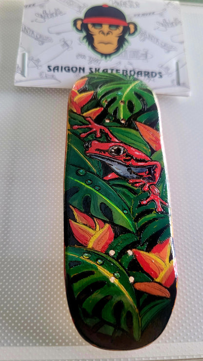 Green jungle fingerboard deck with red lizard illustration and orange leaf accents