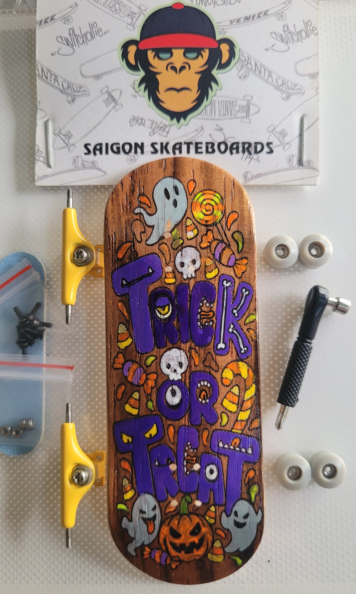 Skateboard deck with Halloween artwork, shown with gold trucks and white wheels