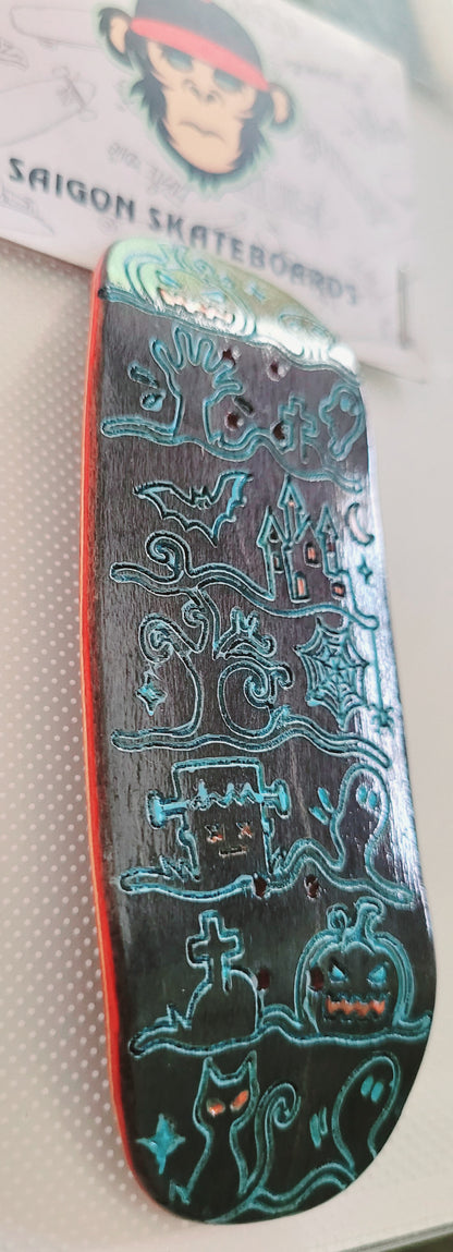 Close-up skateboard deck with teal Ghost Town line art and dark graphic background