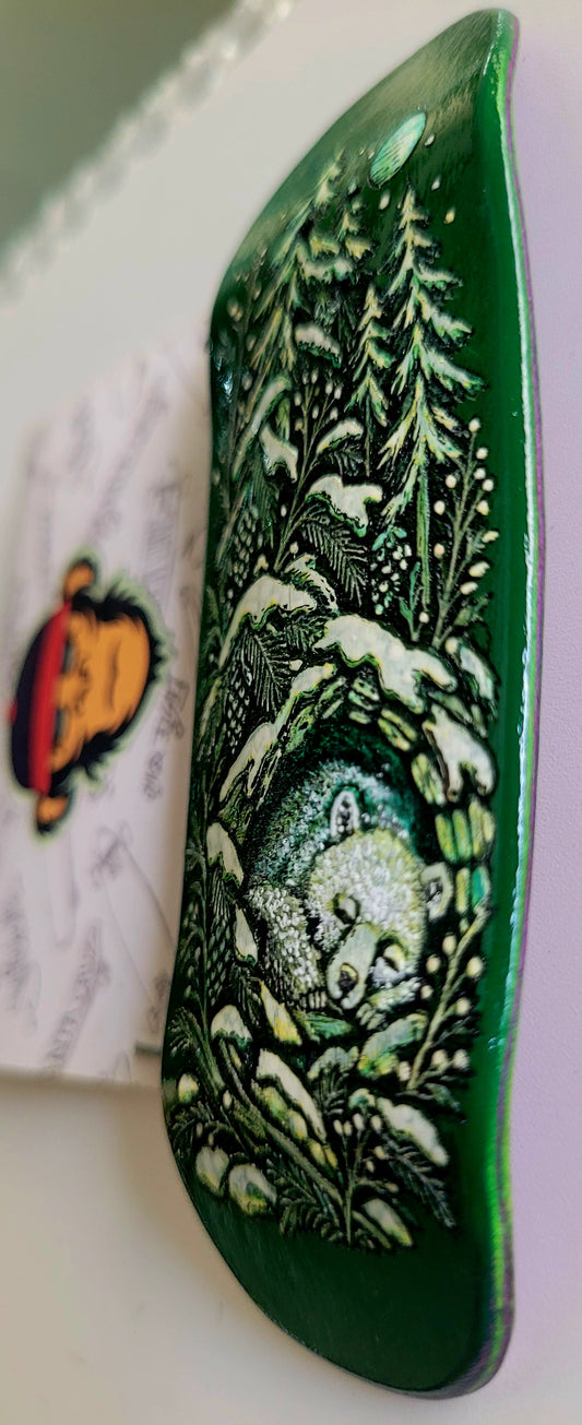 Dark green skateboard deck side view with detailed forest, moon, and animal illustration