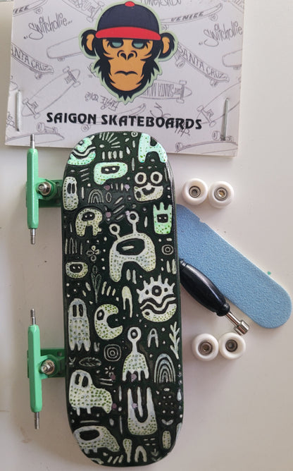 Medium fingerboard with black monster doodle deck, green wheels, and silver trucks.