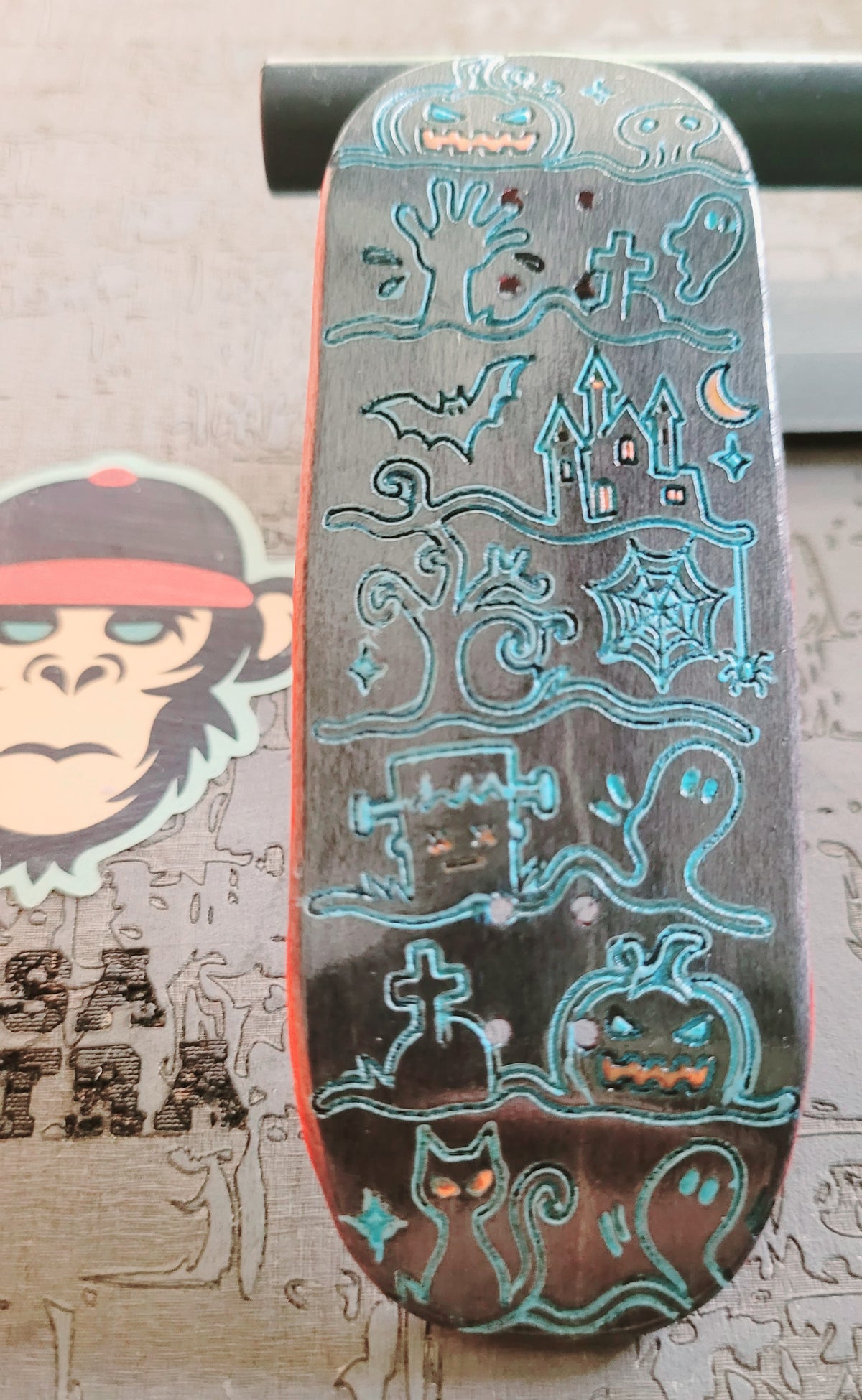 Skateboard deck with blue engraved Ghost Town graphics and red side stripe