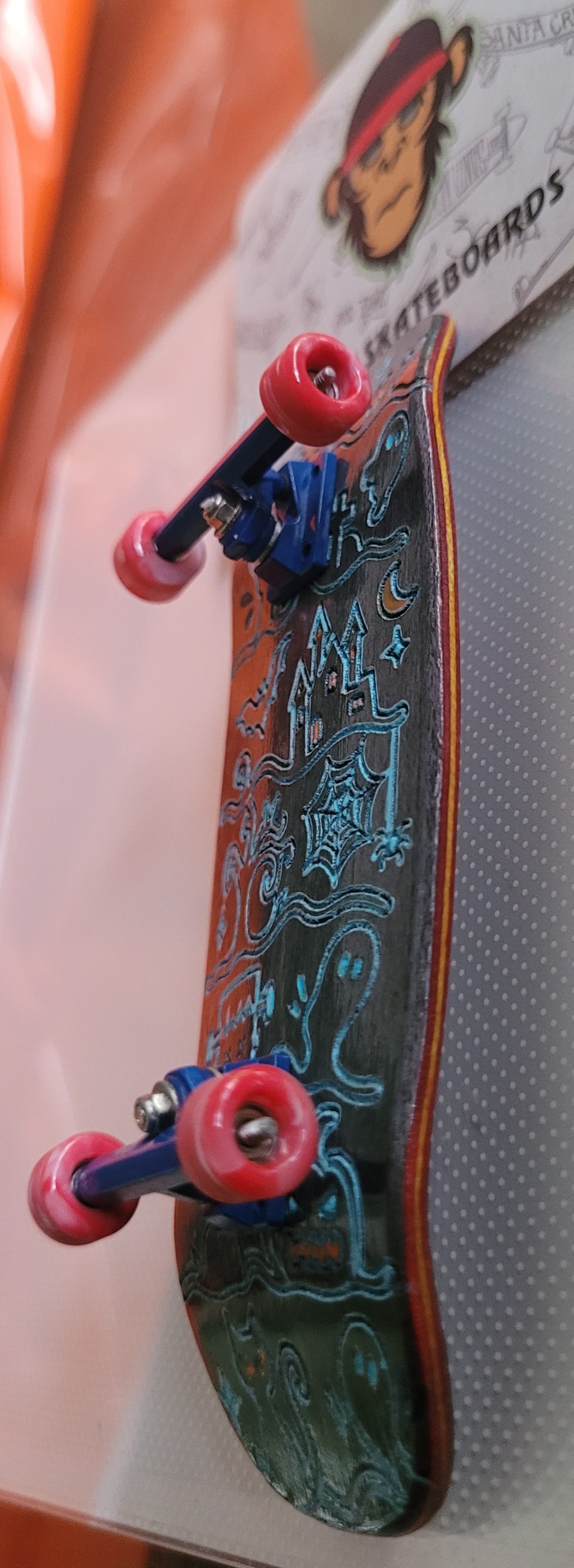 Side view skateboard with Ghost Town deck, blue trucks, and red wheels