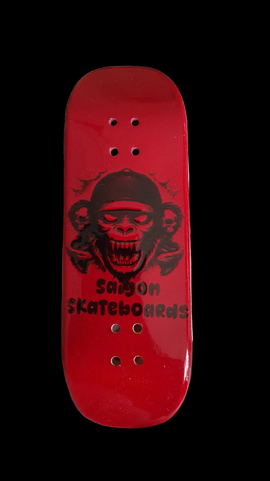 Red skateboard deck with a black graphic held in a hand on a light-colored surface