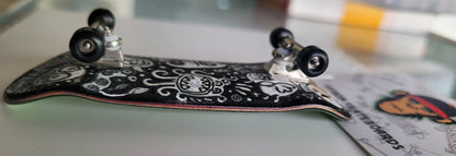 Black medium fingerboard with white monster doodle graphics and silver trucks.
